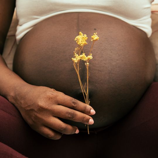 Pregnant woman holding flower.